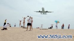 Tourists pose for photographs as an airplane descends into Phuket International Airport.